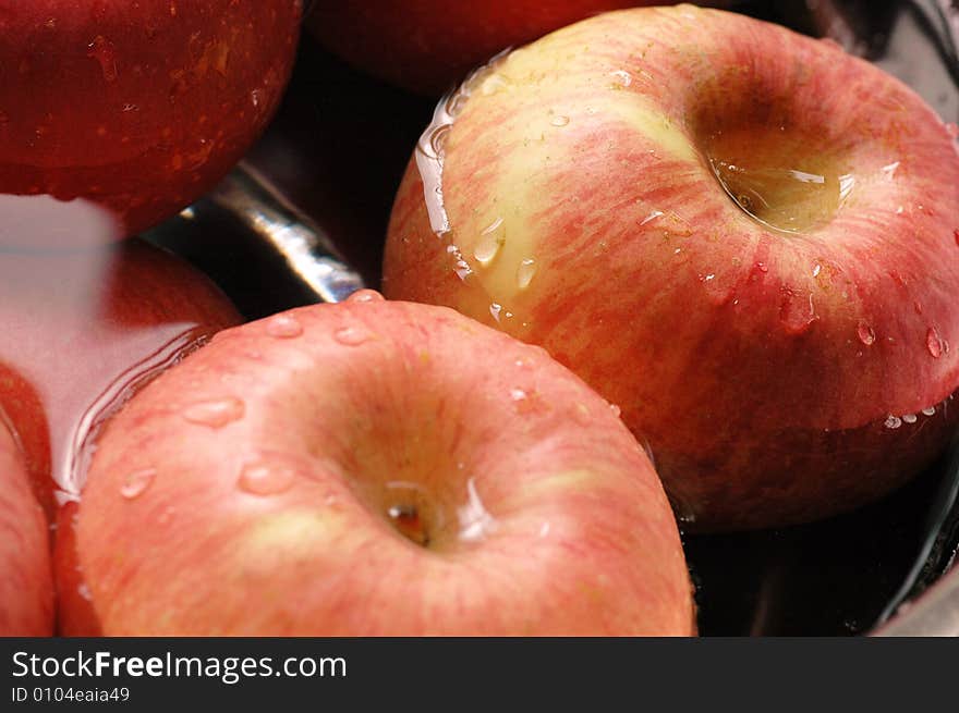 Fresh red apples floating on water in container