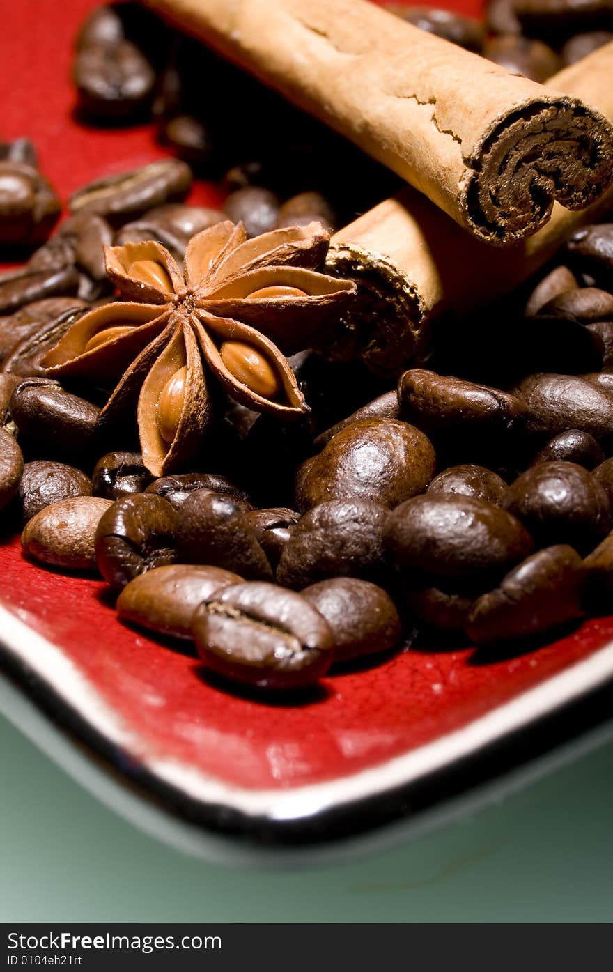 Coffee beans and cinnamon sticks on red plate with anice. Coffee beans and cinnamon sticks on red plate with anice