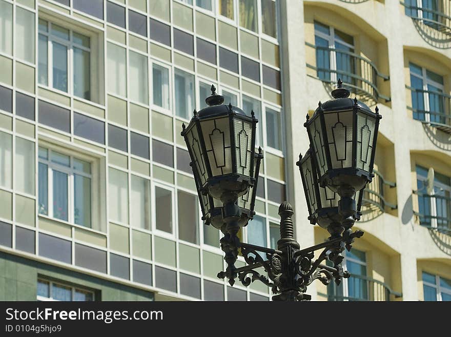 Old street lamp stands beside a new modern building