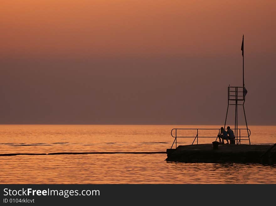 Silhouette of a life tower and a young couple.