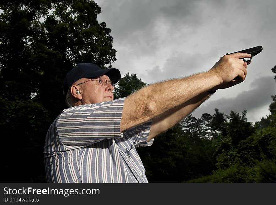 An older man practising his pistol marksmanship.