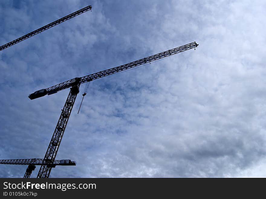 Big construction cranes silhouette midday