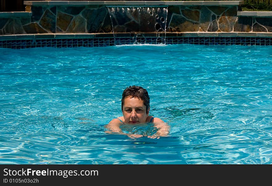 Middle aged woman swimming towards the camera in pool. Middle aged woman swimming towards the camera in pool