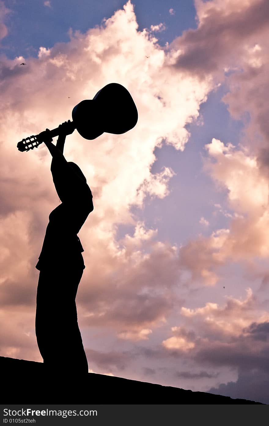 Guitarist throwing her instrument at dusk.