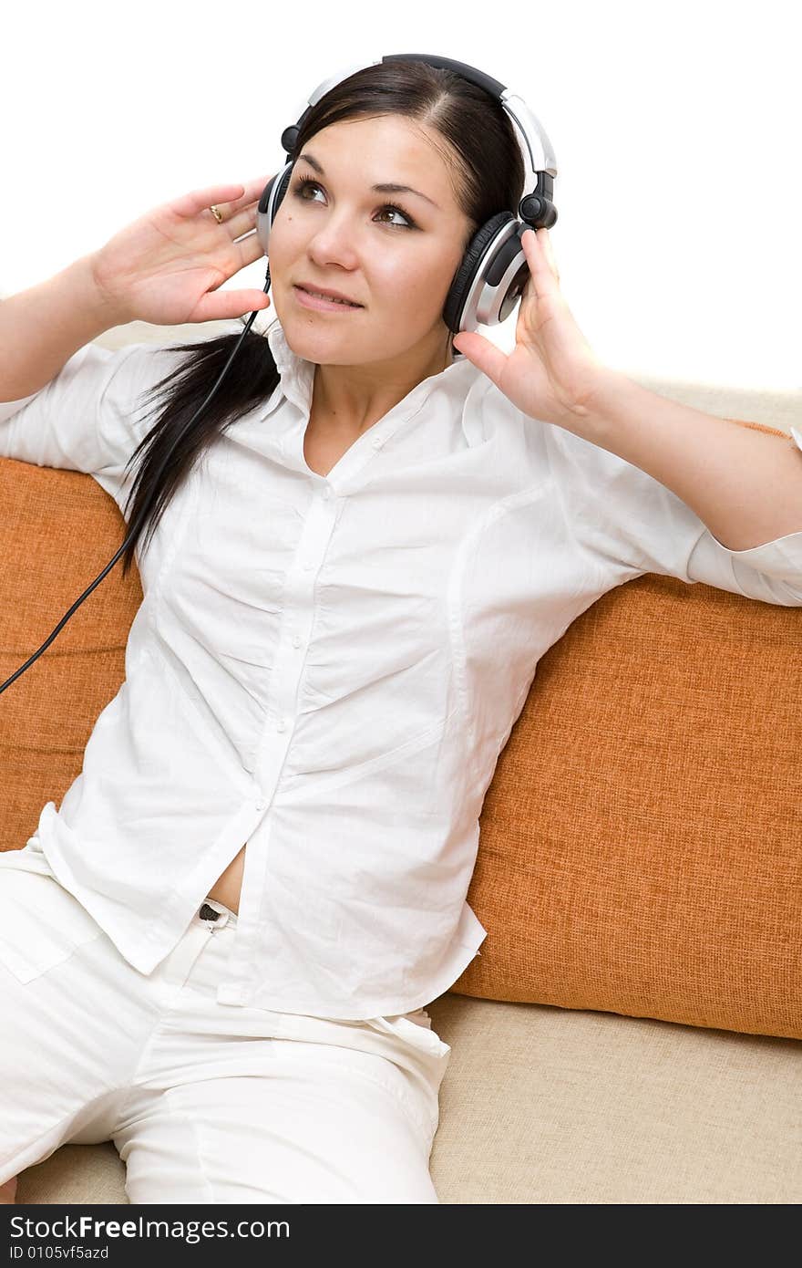 Attractive brunette woman with headphones on sofa. Attractive brunette woman with headphones on sofa