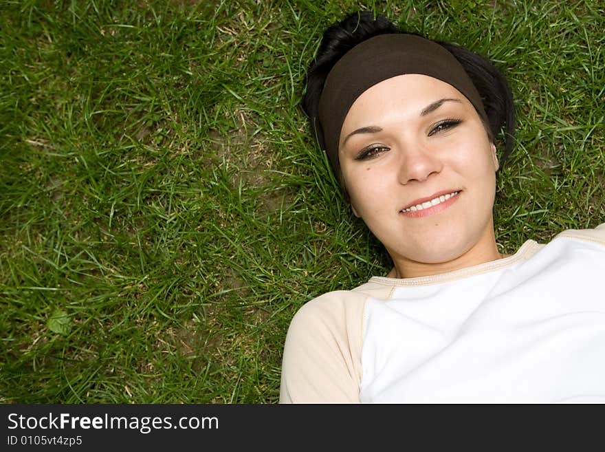 Attractive brunette woman lying on grass. Attractive brunette woman lying on grass