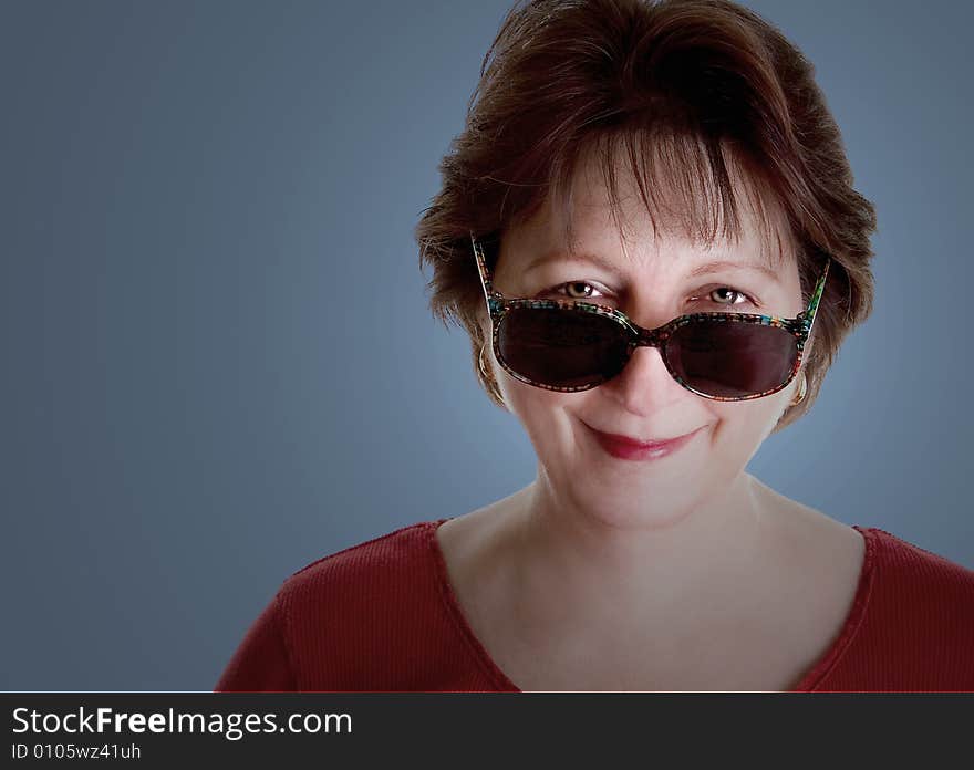 An attractive middle aged woman looking over her sunglasses. An attractive middle aged woman looking over her sunglasses