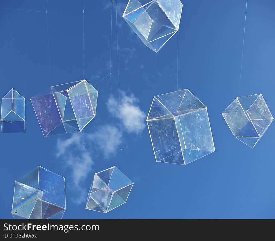 Installation art piece with floating perspex houses suspended on wire to look like polygonal soap bubbles, against blue sky with fluffy cloud. Installation art piece with floating perspex houses suspended on wire to look like polygonal soap bubbles, against blue sky with fluffy cloud