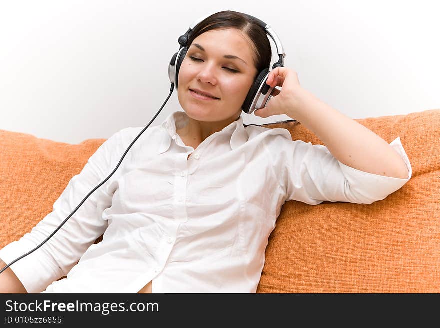 Attractive brunette woman with headphones on sofa. Attractive brunette woman with headphones on sofa