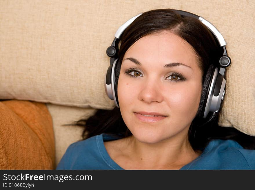 Attractive brunette woman with headphones on sofa. Attractive brunette woman with headphones on sofa