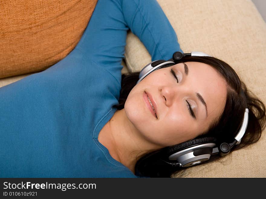 Attractive brunette woman with headphones on sofa. Attractive brunette woman with headphones on sofa