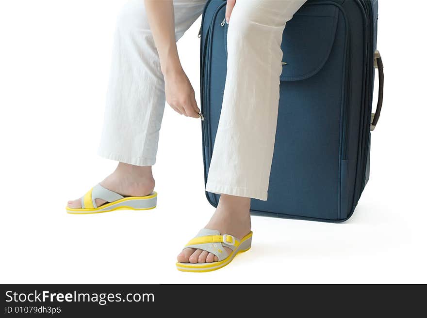 Female sitting on a  suitcase and zipping or unzipping it. Female sitting on a  suitcase and zipping or unzipping it