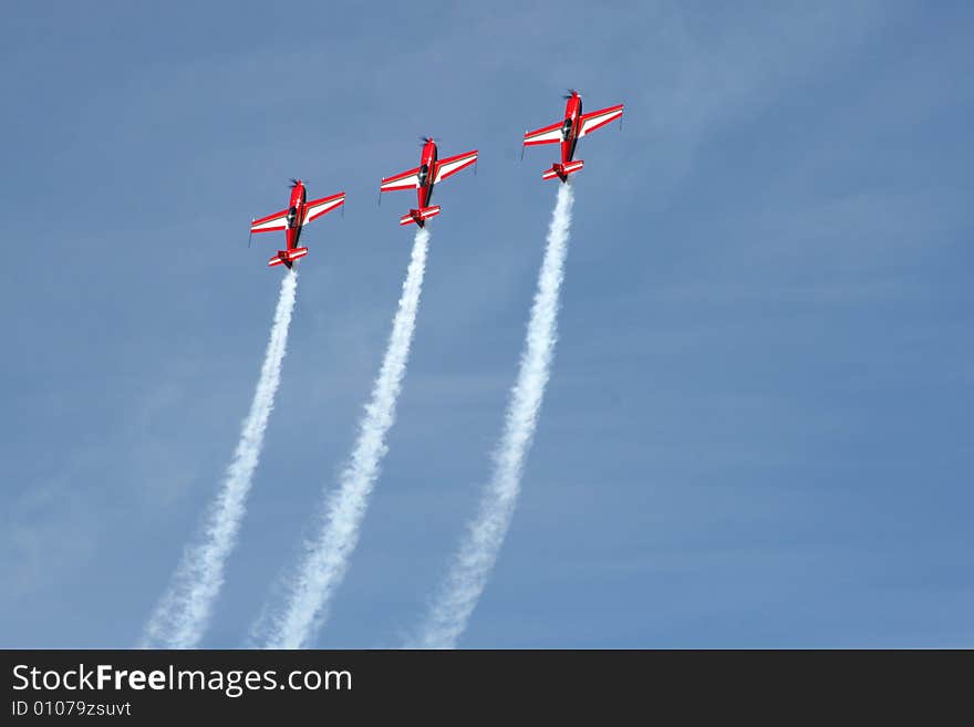 Formation aerobatics aircraft climbing in unison with smoke trails