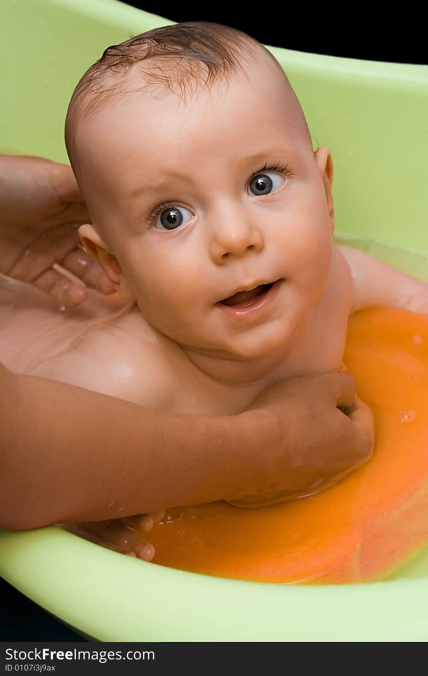 Adorable infant (a boy) lying in green bathtub and rising his head. Adorable infant (a boy) lying in green bathtub and rising his head