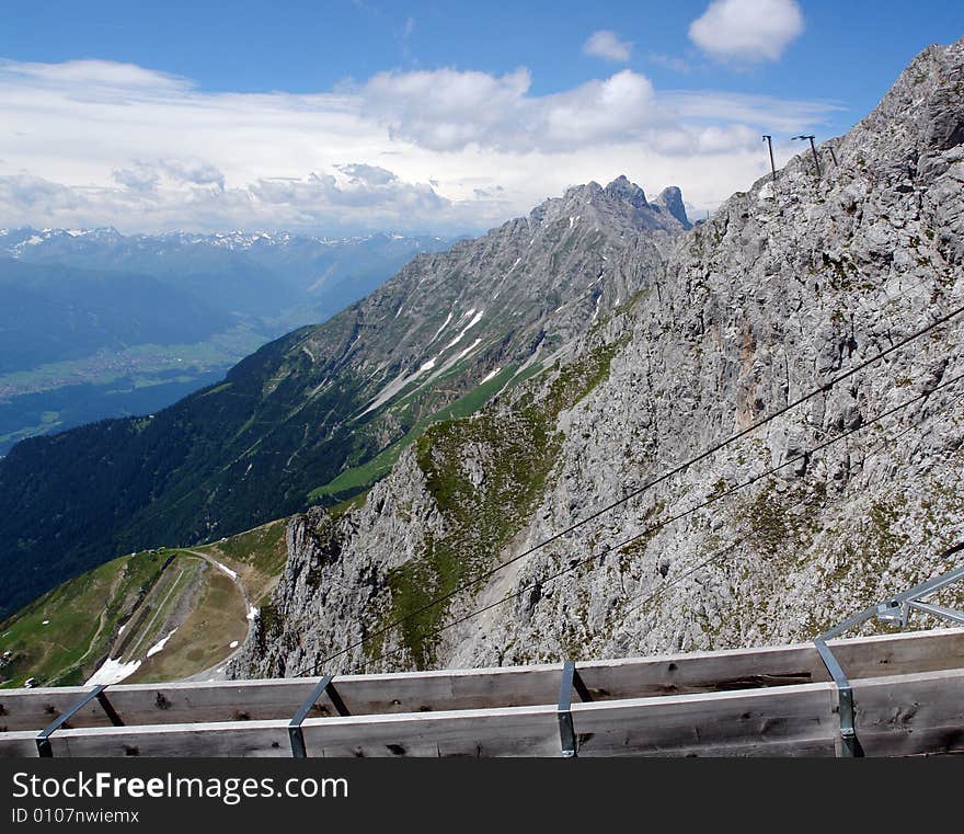 Clouds above the mountains Austrian Alpes . The snow on the rocks. Sight from the peak of Hafelkarspitze mountain .Not so far from Innsbruck . Part of the wood construction of tourist peak station . Clouds above the mountains Austrian Alpes . The snow on the rocks. Sight from the peak of Hafelkarspitze mountain .Not so far from Innsbruck . Part of the wood construction of tourist peak station .