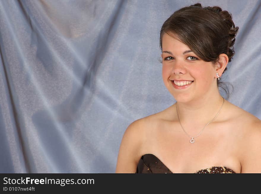 A beautiful smiling young woman with hair and makeup done.  Room for copy on left.