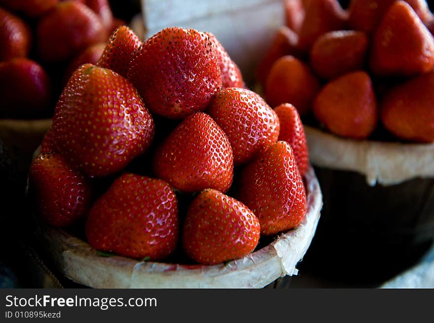 An image of small bushels filled with plump vibrant strawberries