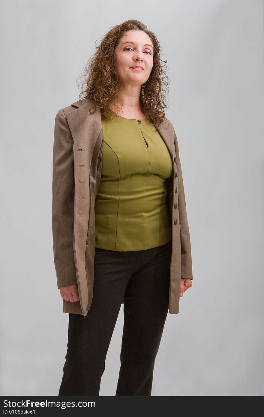 Happy business woman dressed in a green shirt, black pants and brown blazer, isolated