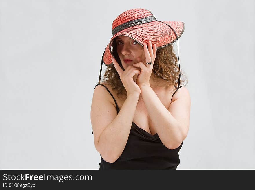 Middle aged woman wearing a red hat bending it with both hands so she can peek through, isolated. Middle aged woman wearing a red hat bending it with both hands so she can peek through, isolated