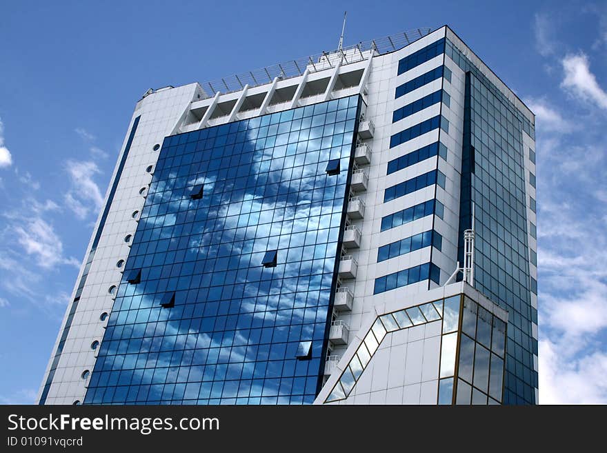 Blue with white a skyscraper with reflection of clouds