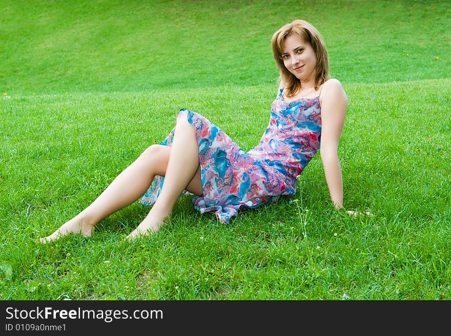 Young attractive girl sits on a green grass. Young attractive girl sits on a green grass