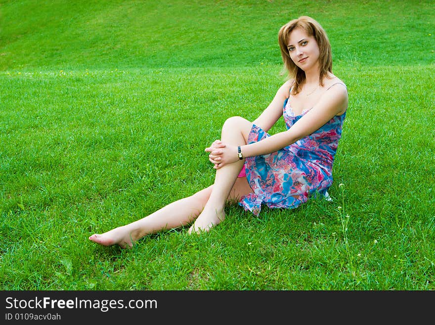 Young attractive girl sits on a green grass. Young attractive girl sits on a green grass