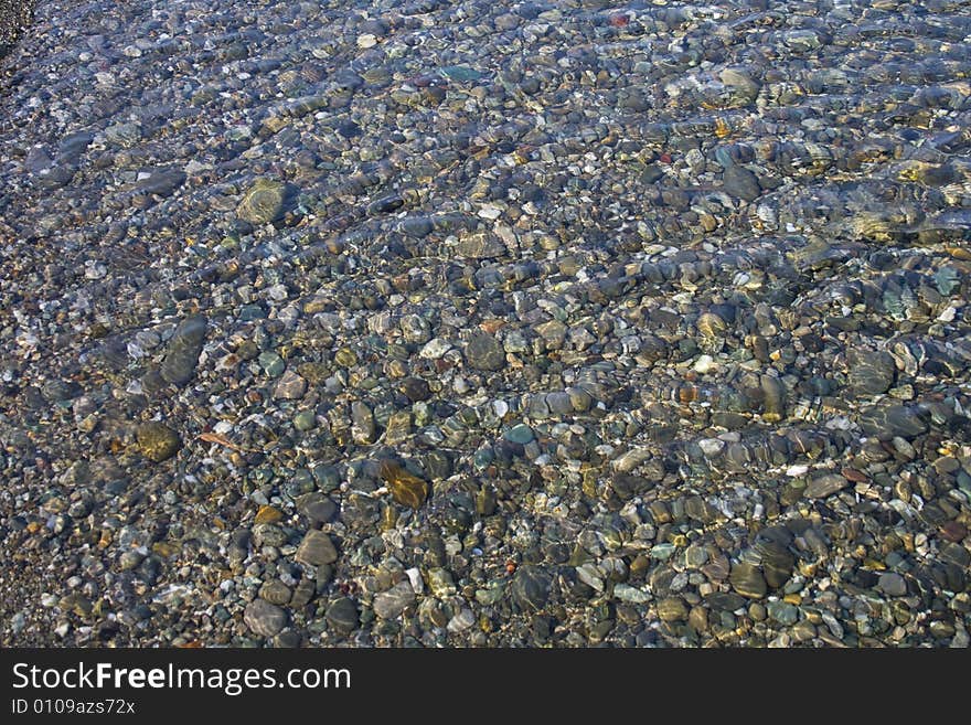 Ripiling water over colurful pebbles stones. Ripiling water over colurful pebbles stones