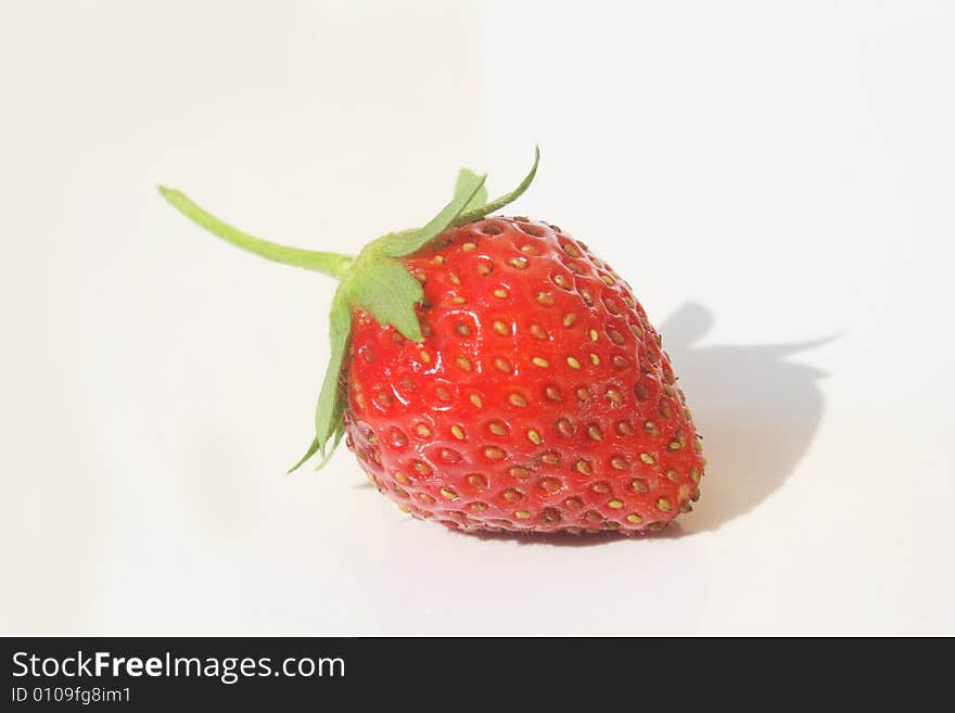 Single red ripe strawberry against white background