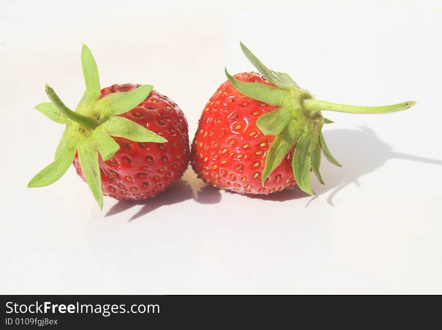 Two wild strawberries against white background