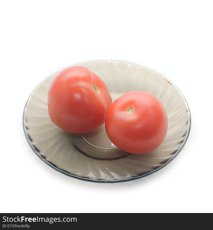 Two tomatoes on dark plate isolated on white