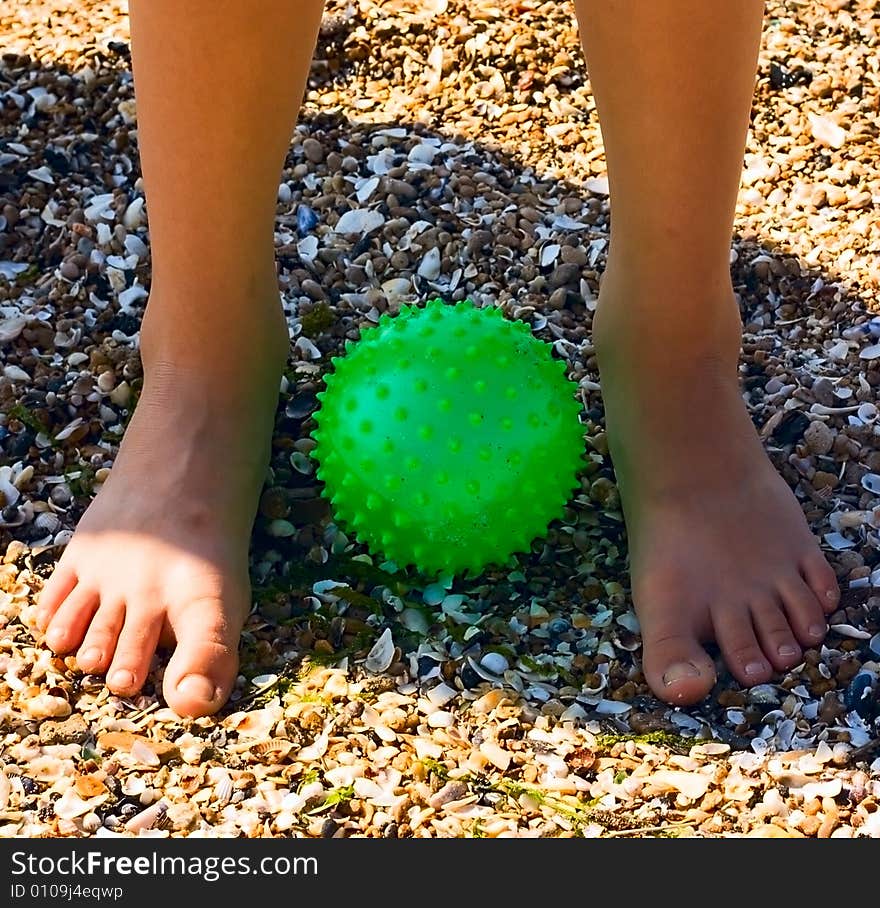 Child Feet on sand at green ball