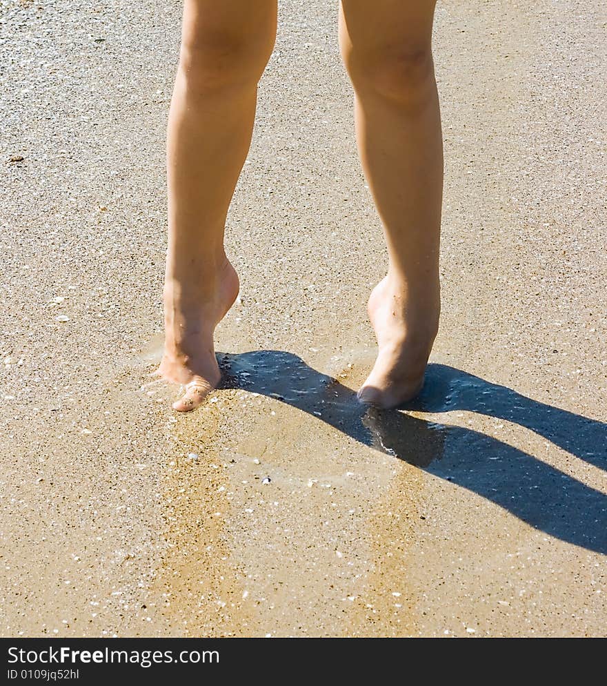 Child legs on sand with shadow