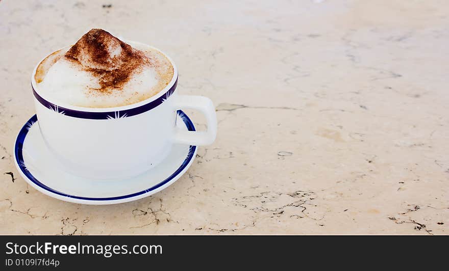 Cup of cappuccino with cacao and sugar on a marble table