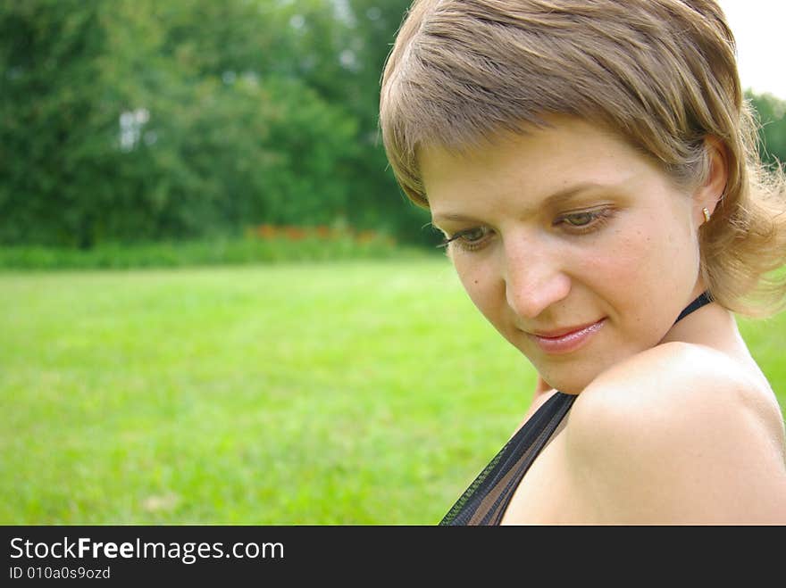 Attractive young woman against green grass. Attractive young woman against green grass