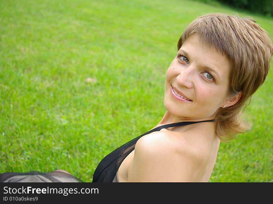 Attractive young woman against green grass. Attractive young woman against green grass