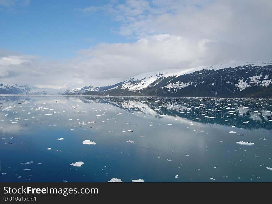 Snowy mountains in Alaska reflect off the beautiful blue bay water. Snowy mountains in Alaska reflect off the beautiful blue bay water.