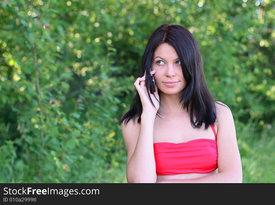 Young woman is talking on the phone in the garden. Young woman is talking on the phone in the garden