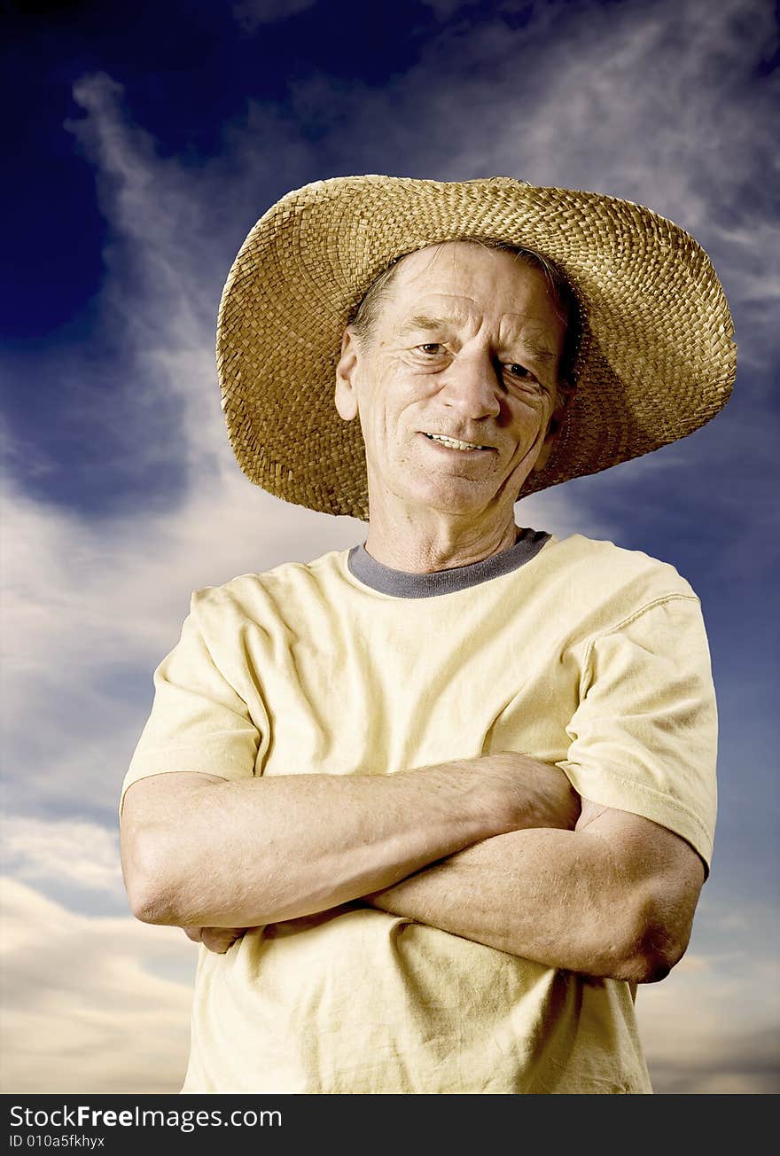 Senior man in a straw hat in front of cloudy sky. Senior man in a straw hat in front of cloudy sky