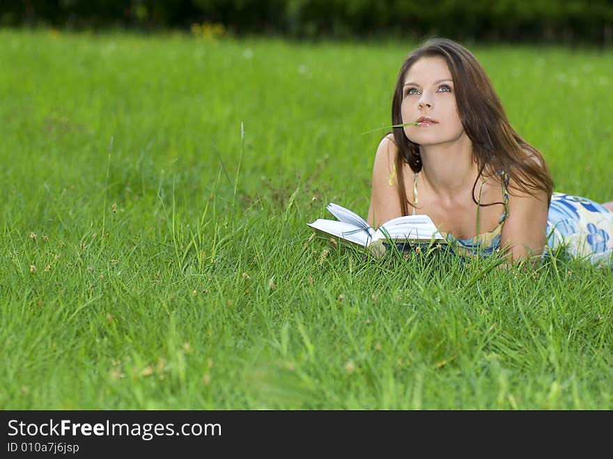 Young woman reading book in park.