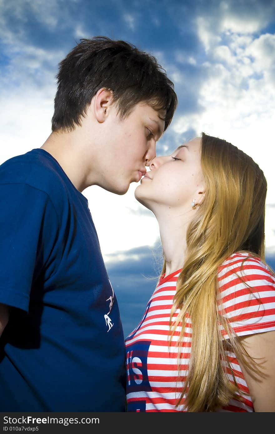 Love concept: kissing couple on a background of the blue sky