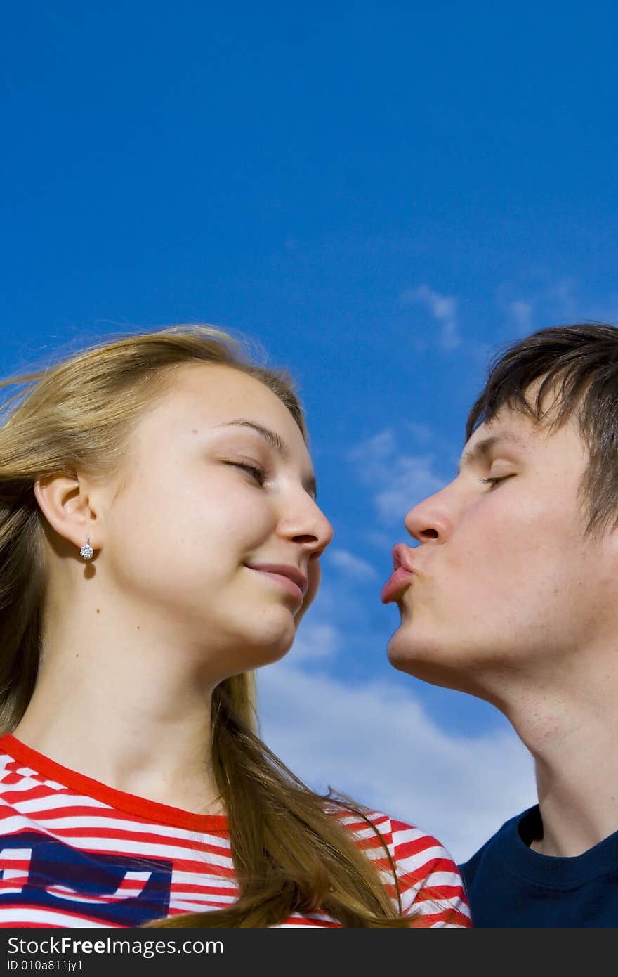 Love concept: kissing couple on a background of the blue sky