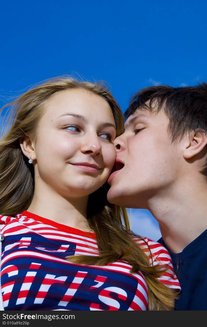 Love concept: kissing couple on a background of the blue sky