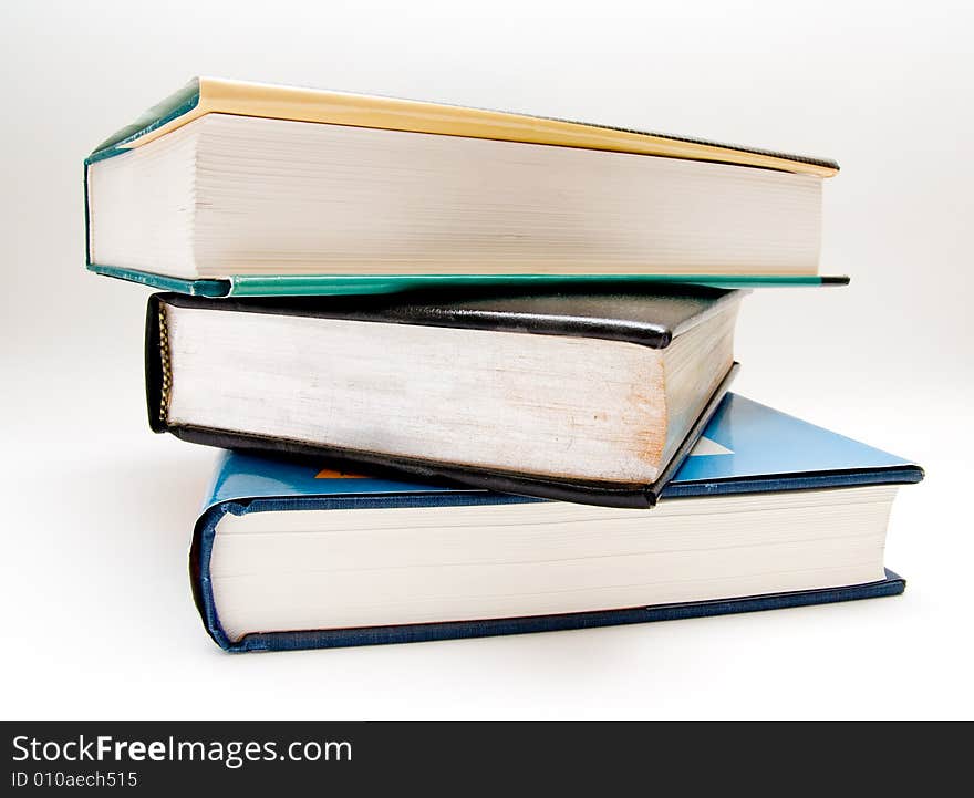 Three large textbooks stacked on top of each other. Three large textbooks stacked on top of each other.