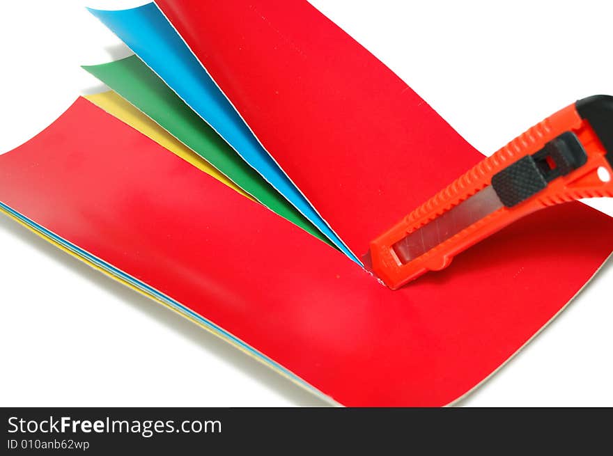 The knife cuts a color paper isolated on a white background. The knife cuts a color paper isolated on a white background