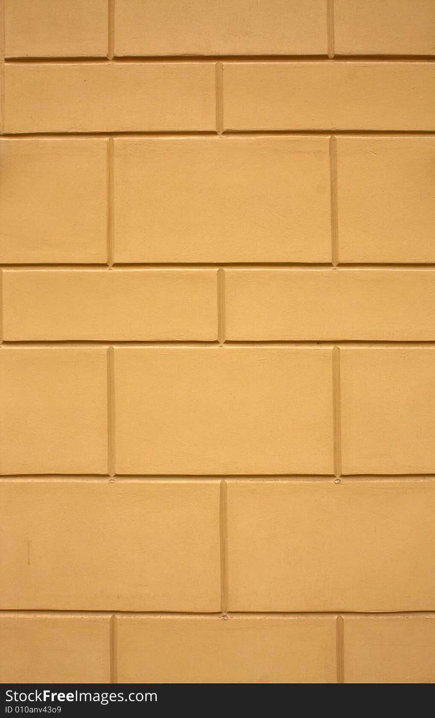 The yellow plastered wall with a regular relief.