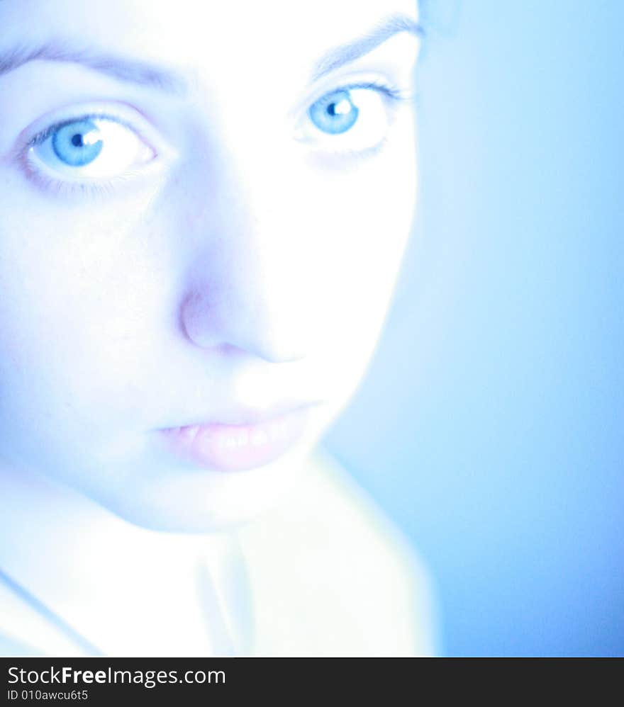 The young girl with blue eyes. A blue background. The young girl with blue eyes. A blue background