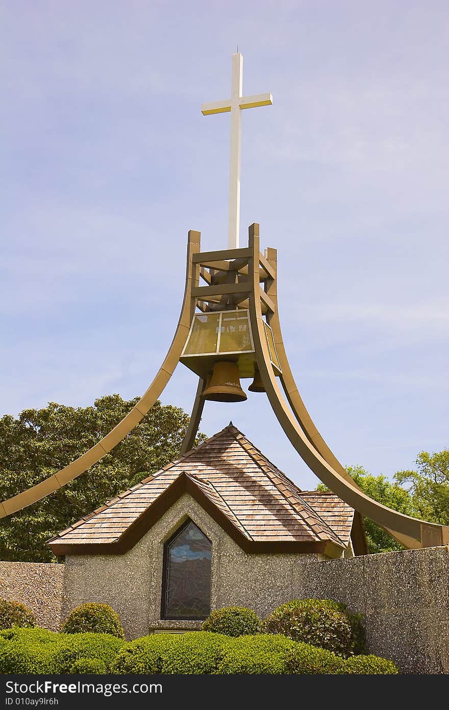 A bell tower and a cross on a display in a public park. A bell tower and a cross on a display in a public park