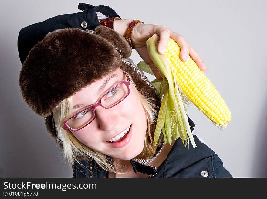 Young woman staring at cob of corn.