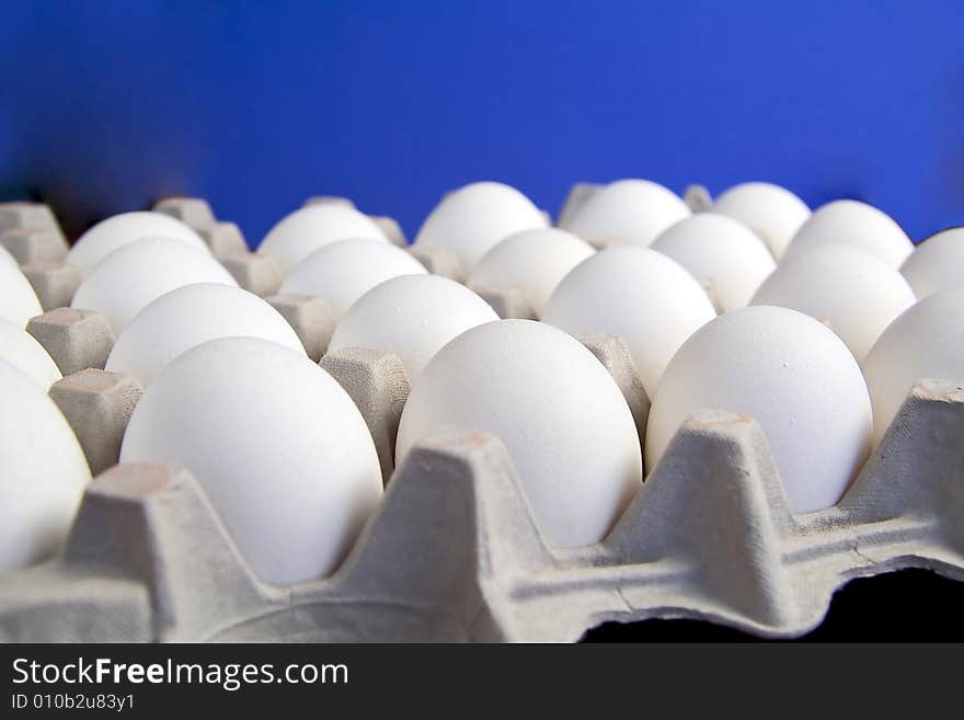 A couple of dozen eggs with blue background