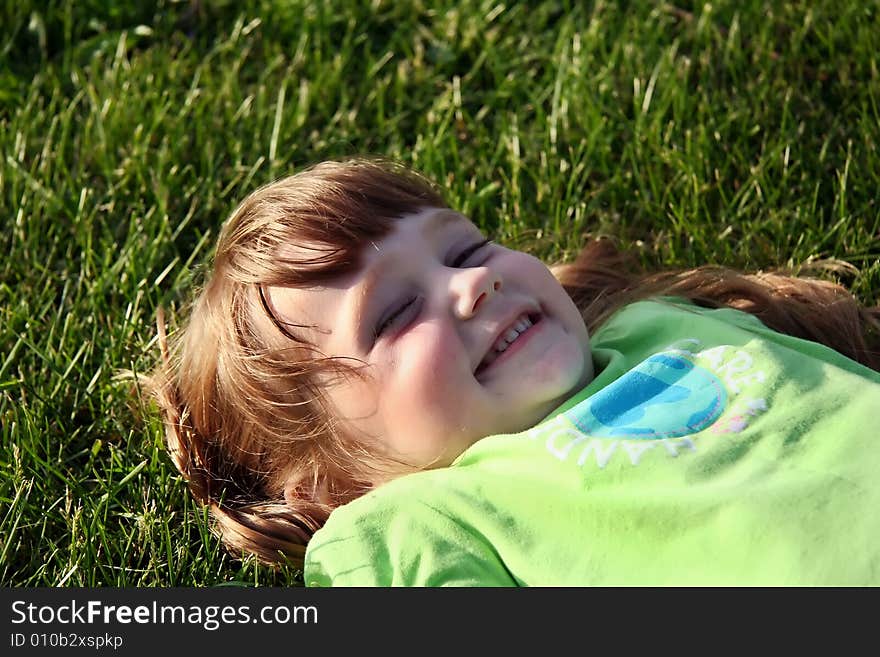 A happy little girl laying in the grass